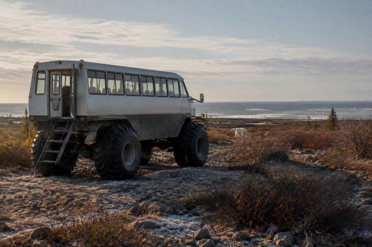 A raised tundra vehicle parked on open subarctic ground near Hudson Bay