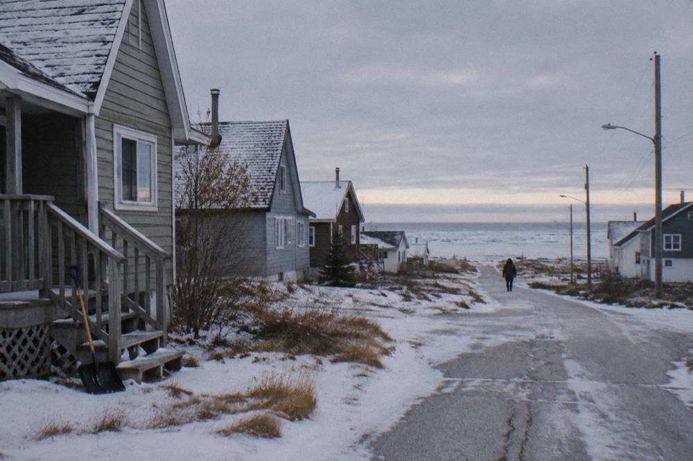 A Churchill street in late autumn with light snow on the ground and low buildings under a grey sky