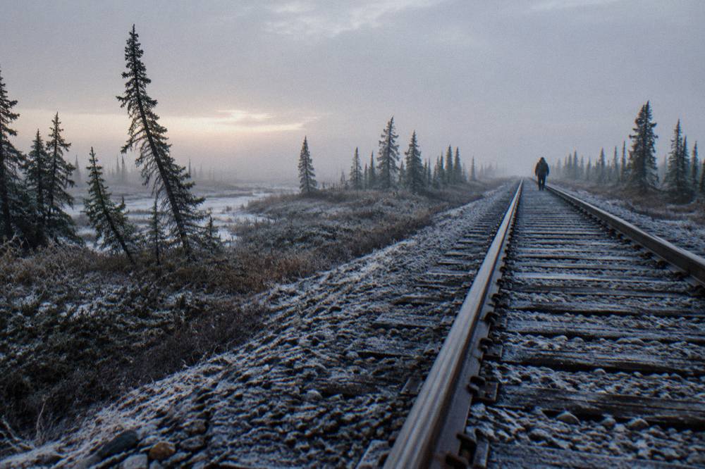 A rail line cutting straight through flat boreal forest and bogland in northern Manitoba.