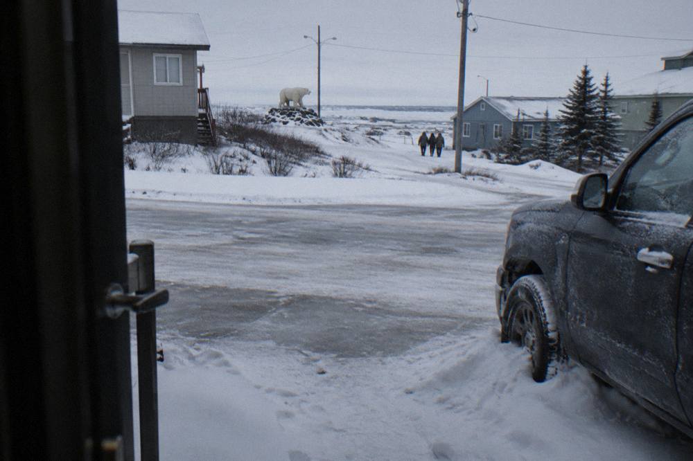 A parked truck with its door handle visible on a snowy street in a small northern town