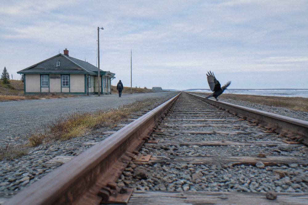 Railway tracks running straight across empty tundra toward the horizon under a wide sky