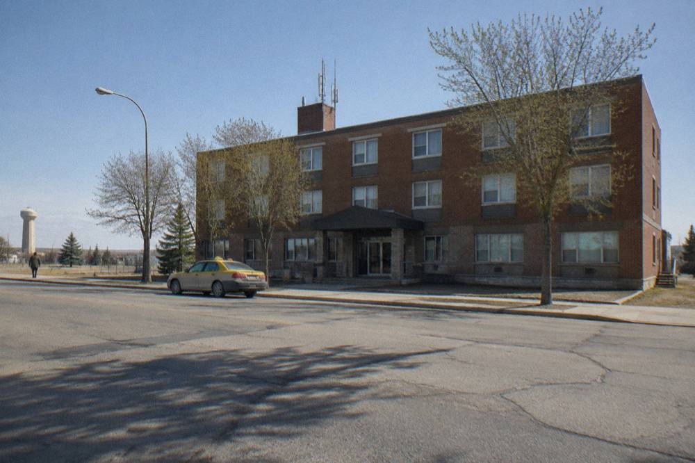 A hotel exterior on a wide prairie avenue under a clear morning sky