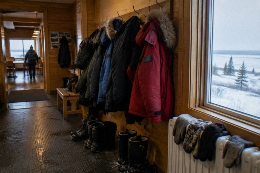 A rack of heavy winter parkas hanging inside a wooden building
