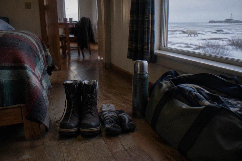A pair of heavy insulated winter boots and thick socks set out on a wooden floor